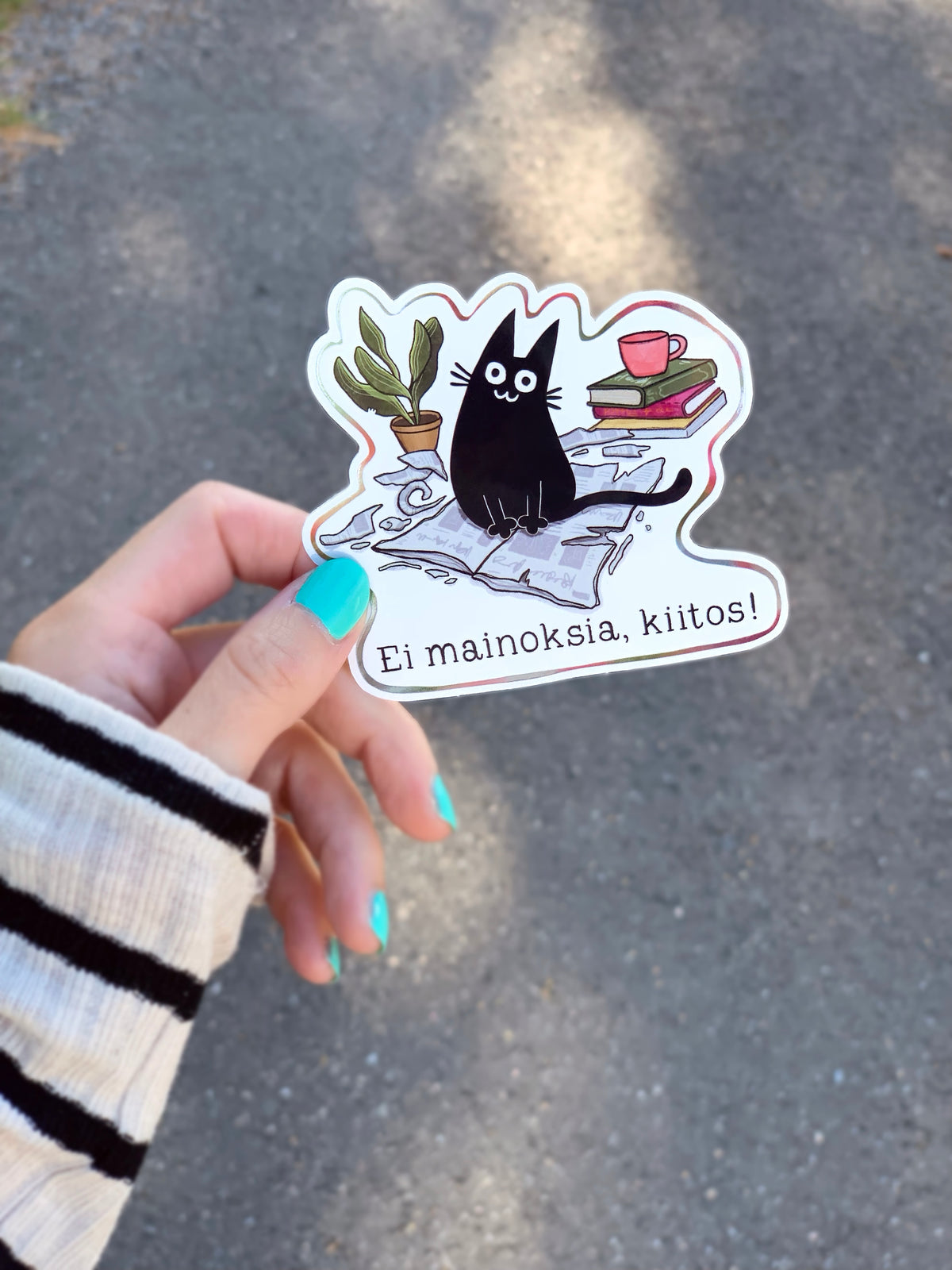 Vinyl cat sticker showing black cat with books, red mug, and potted plant
