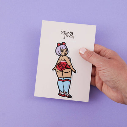 Cartoon vinyl sticker on a card, held by a hand; stylized woman in red top