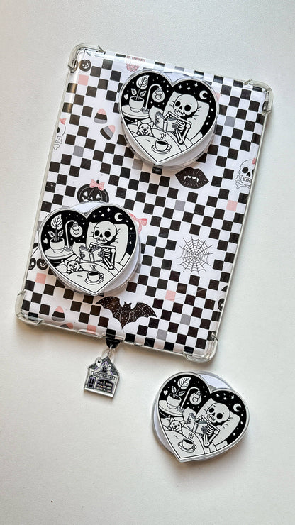 Clear checkerboard phone case with two cartoon heart magnets and dangling keychain charm.