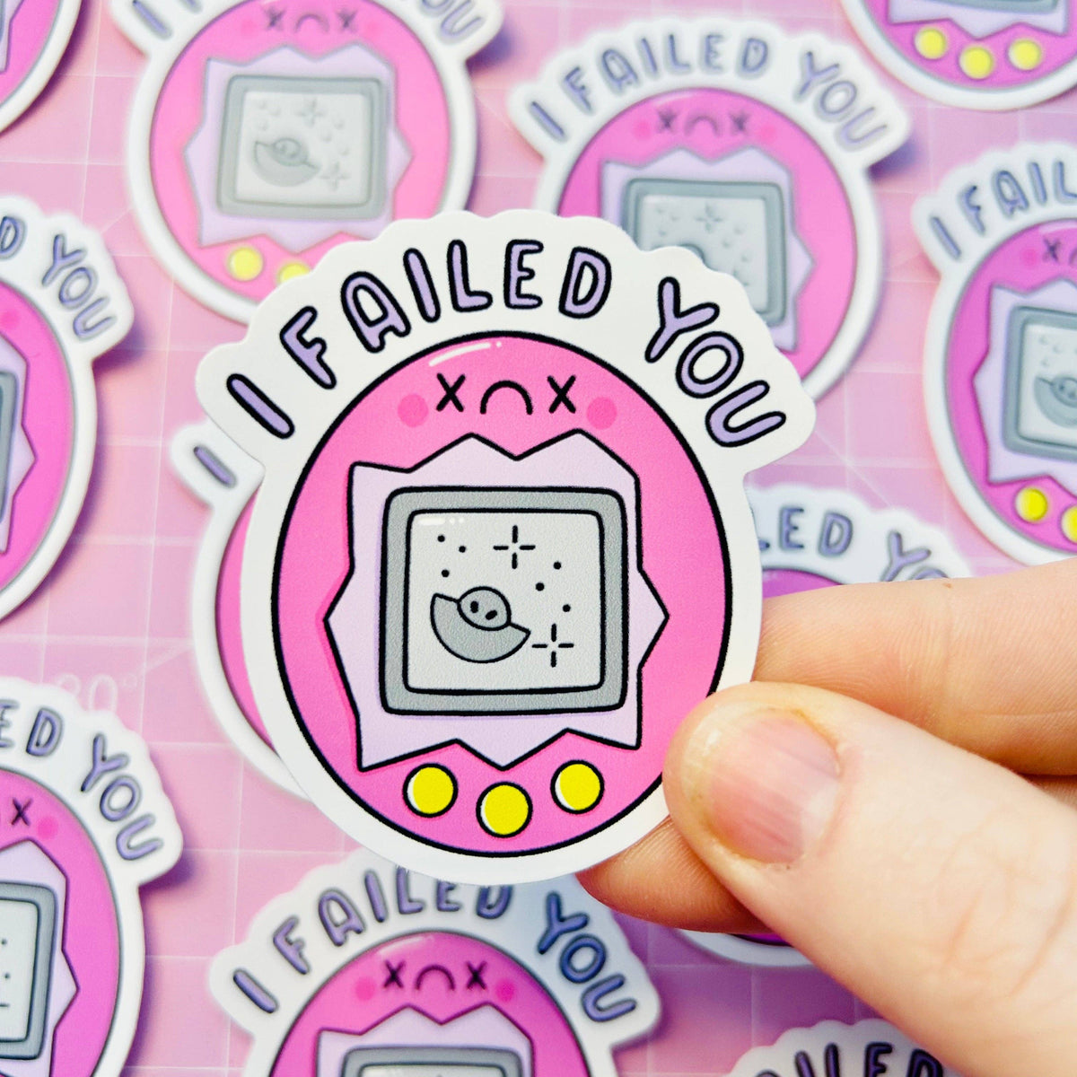 Single vinyl sticker held by fingers, pink “FAILED YOU” game console icon