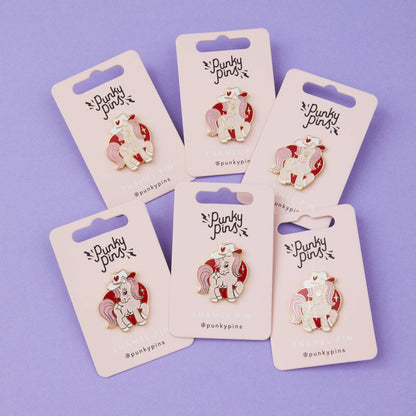 Cowgirl pony enamel pins on backing cards, showing white unicorn with red cowboy hat hearts
