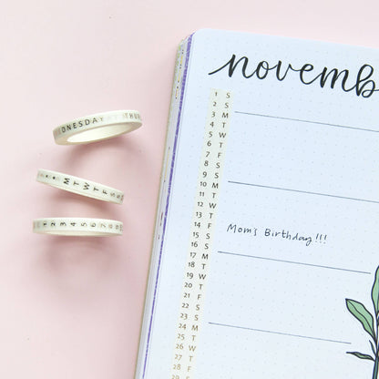 Day-labeled washi tape rolls with “Wednesday” and date numbers beside planner pages