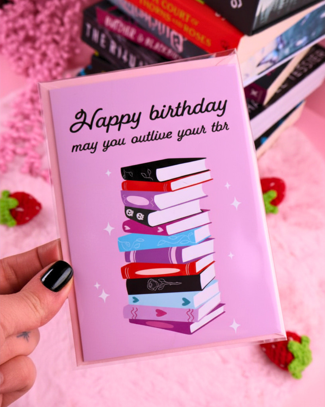 Pink birthday greeting card with stacked books graphic and 'Happy birthday' message