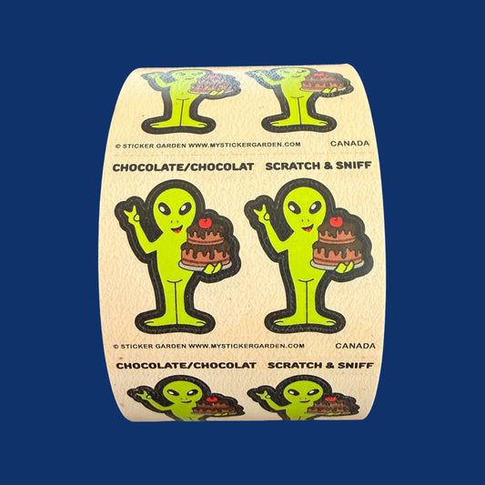 Scratch & sniff sticker roll featuring green alien characters with chocolate cake illustration