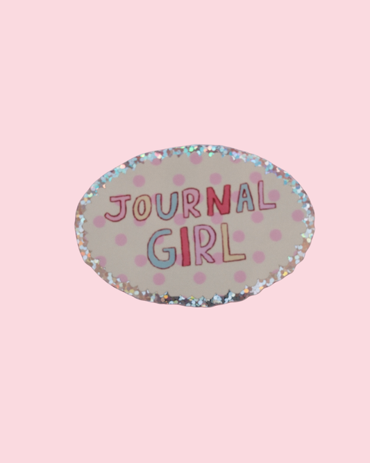 Oval “JOURNAL GIRL” sticker with confetti dots and glittery speckled border on plain background.