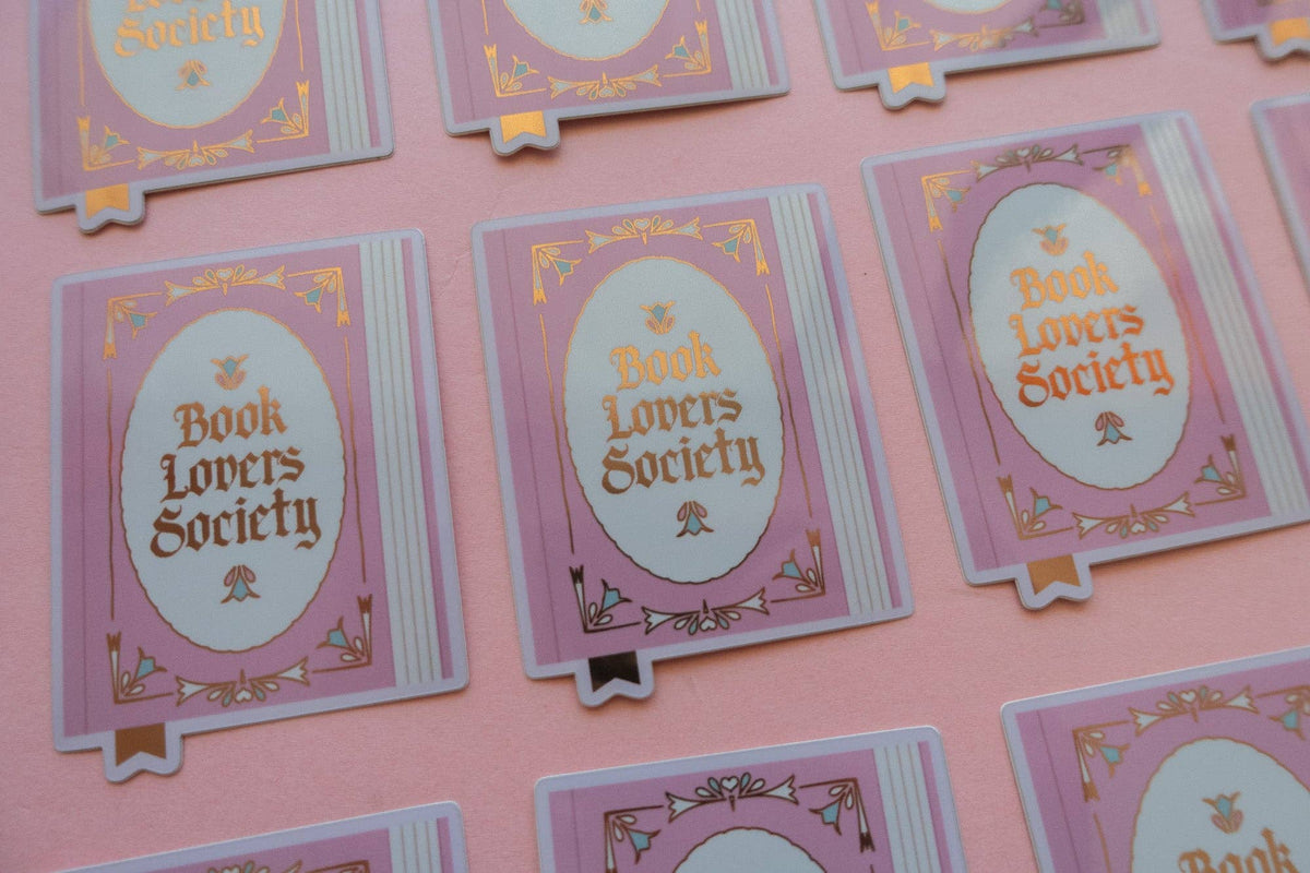 Vinyl sticker cards featuring purple oval “Book Lovers Society” artwork with gold accents
