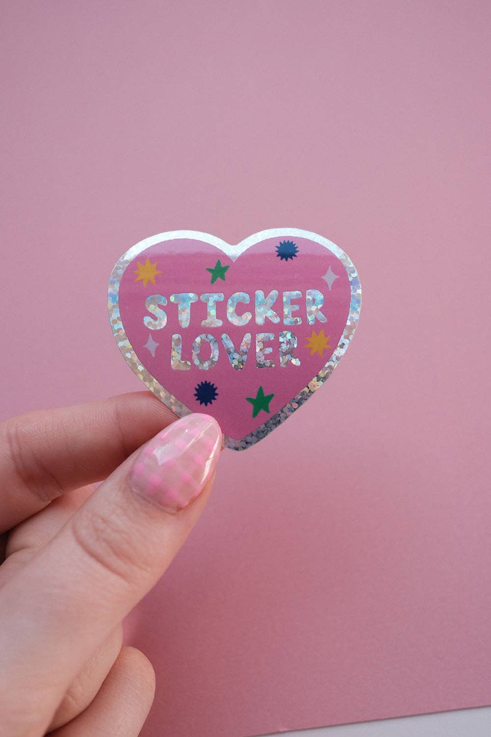Heart sticker held in hand, purple glitter edge with 'STICKER LOVER' stars
