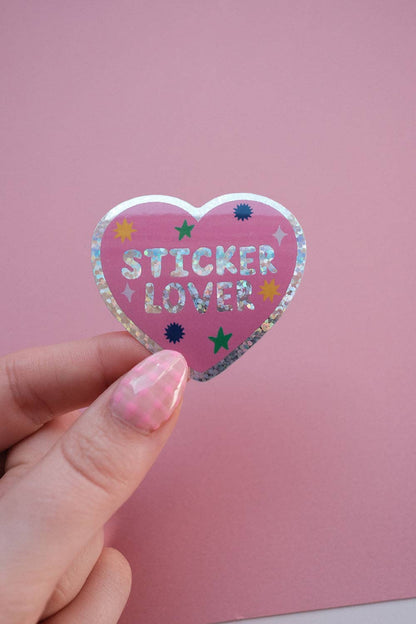 Heart sticker held in hand, purple glitter edge with 'STICKER LOVER' stars