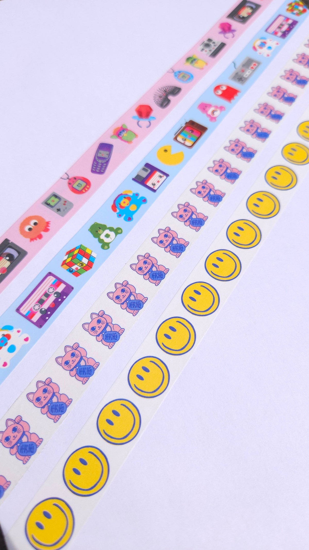 Washi tape strip with repeating cats and yellow smiley icons on light pink