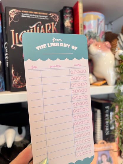 Pink paper bookmark with teal "The Library of" title, lined grid, and rating icons