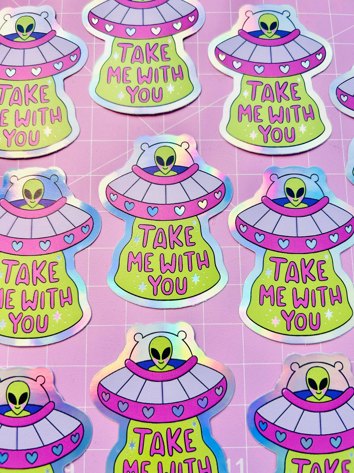 Holographic UFO sticker set showing lime aliens in purple saucers with heart details and text.