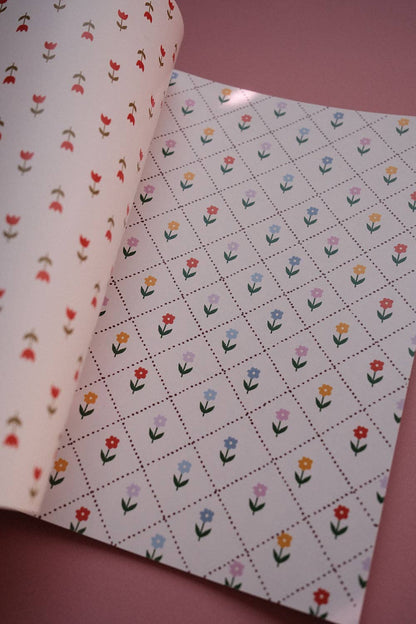 Open scrapbook papers: red tulip pattern on left, white grid of multicolor tulips on right