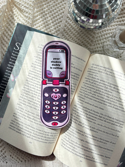 Purple and pink phone-shaped bookmark clipped to open book pages.
