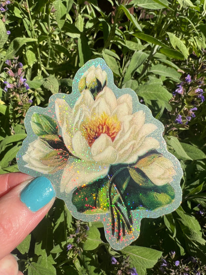 White lotus flower sticker with glitter white blossom and green leaves, held outdoors