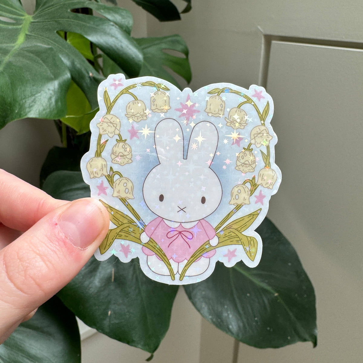 Bunny flower sticker featuring pale blue bunny face, pink bow, and springlike flowers