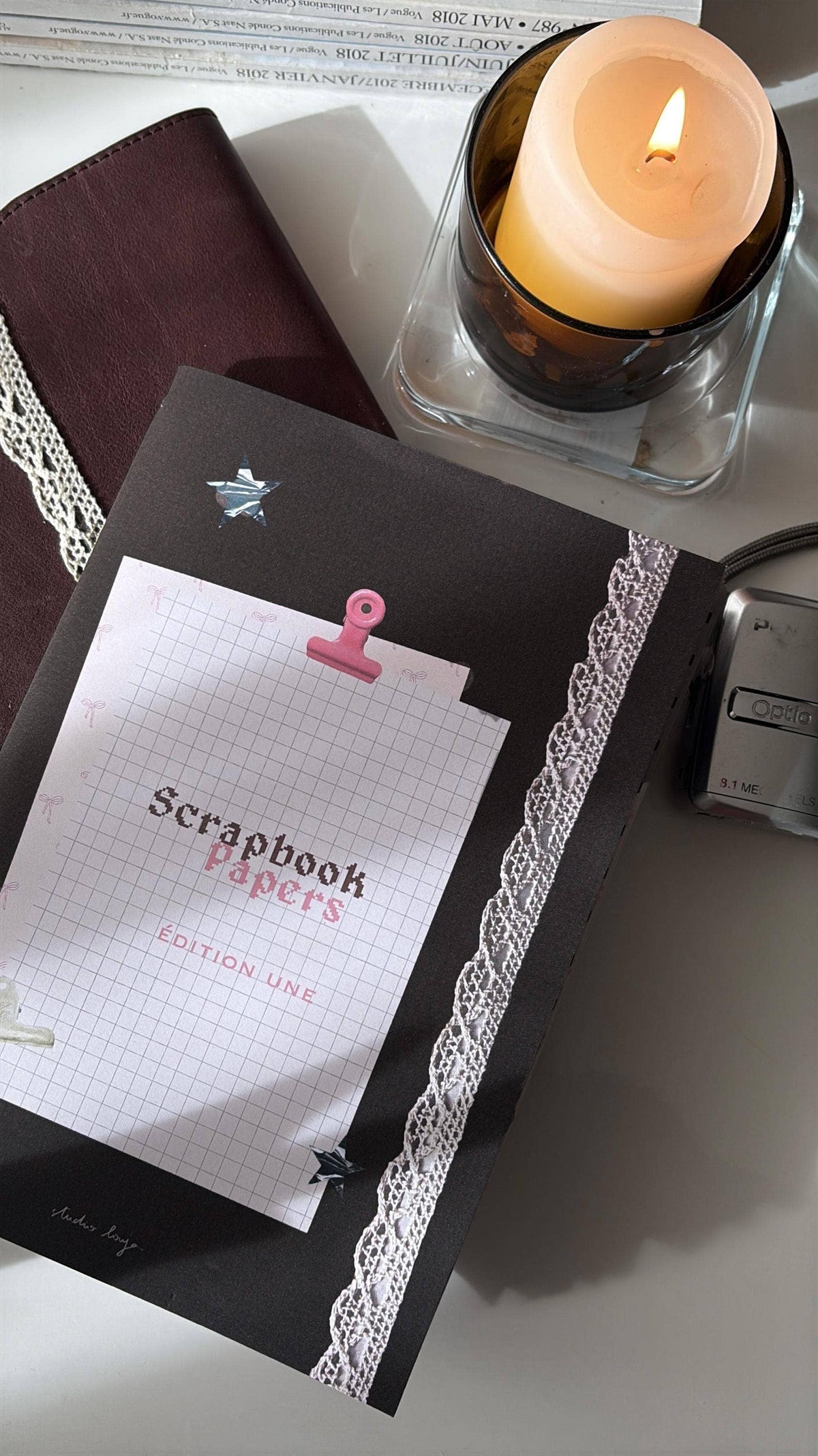 Scrapbook paper stack with maroon pages, lace trim, star and pink binder clip label