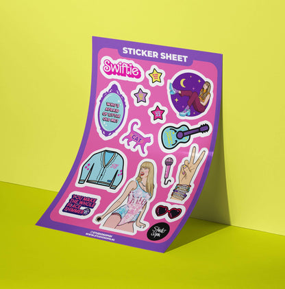 A5 sticker sheet at angle with Swifie artwork: cat, guitar, outfit, stars and hearts