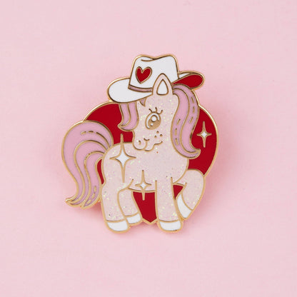 Cowgirl pony glitter enamel pin with white unicorn, red cowboy hat, and heart details