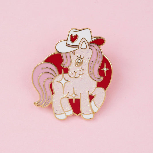 Cowgirl pony glitter enamel pin with white unicorn, red cowboy hat, and heart details
