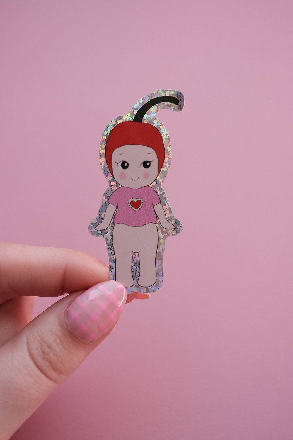 Baby cherry sticker held in hand, cartoon girl with patterned hood and pink heart shirt