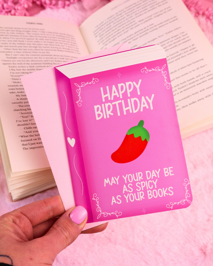 Pink birthday card with 'Happy Birthday' and chili-strawberry icons, held in hand