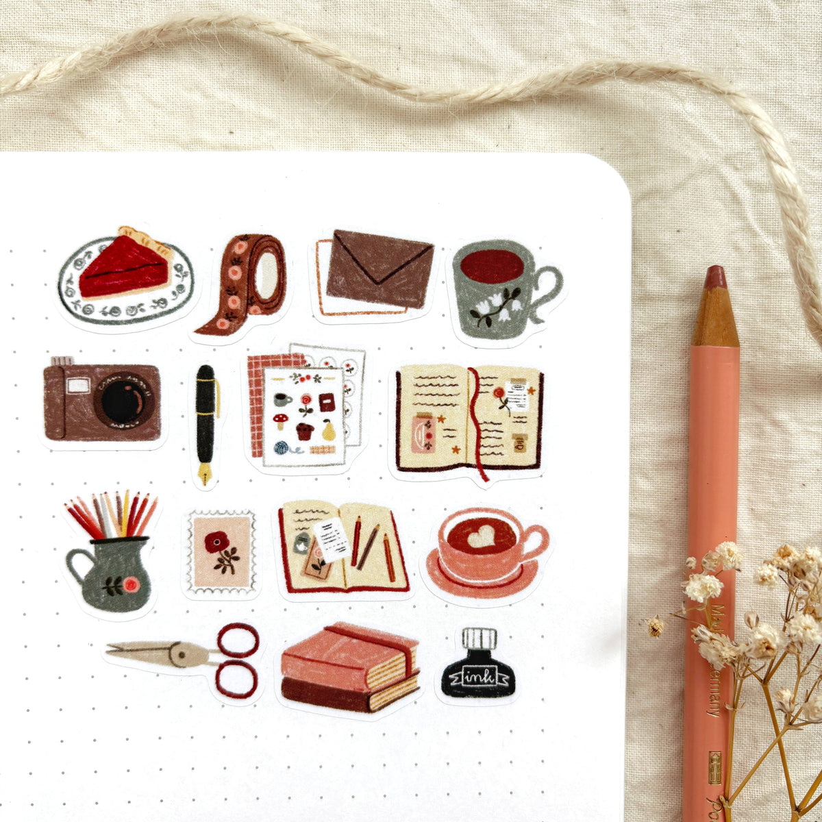 Sticker sheet close-up with teacup, camera, pencils, mug and notebook icons
