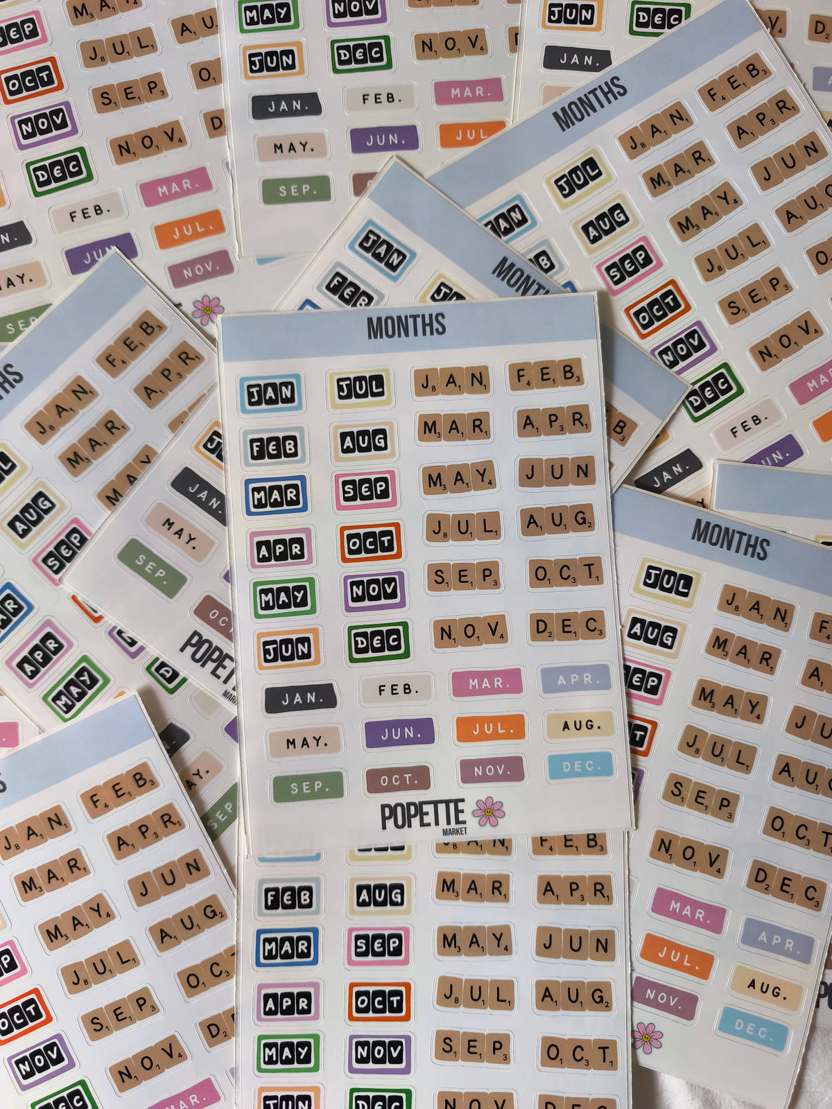 Stacked months A5 sticker sheets with colorful month abbreviation blocks and POPETTE