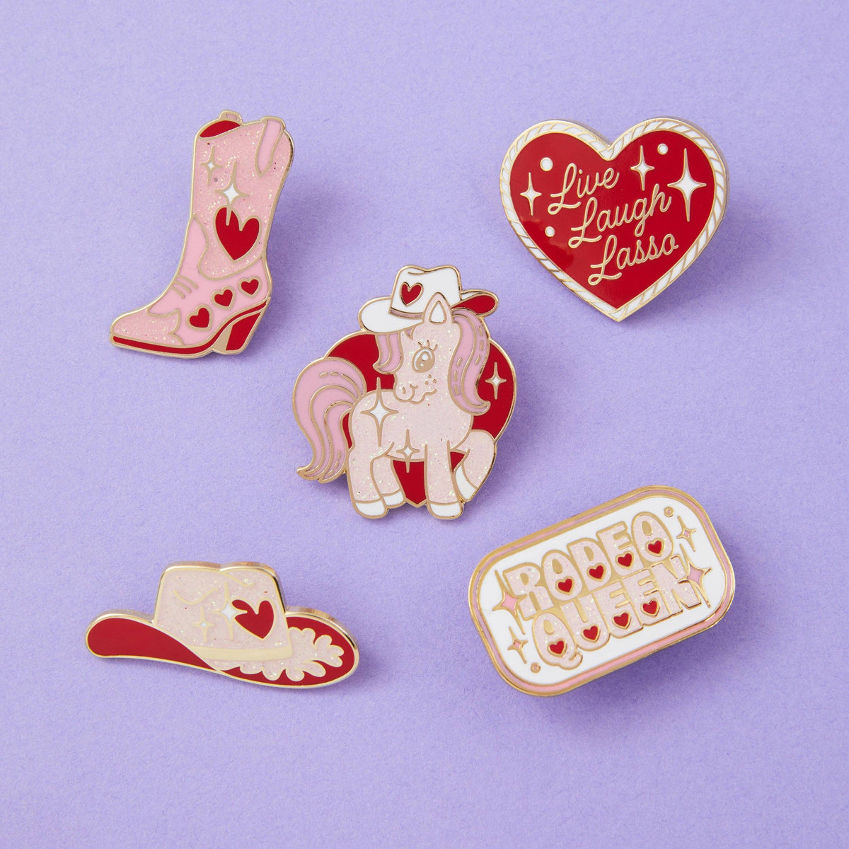 Assorted cowboy-themed enamel pins: white pony, red boots, and heart "Live Laugh Lasso" pin