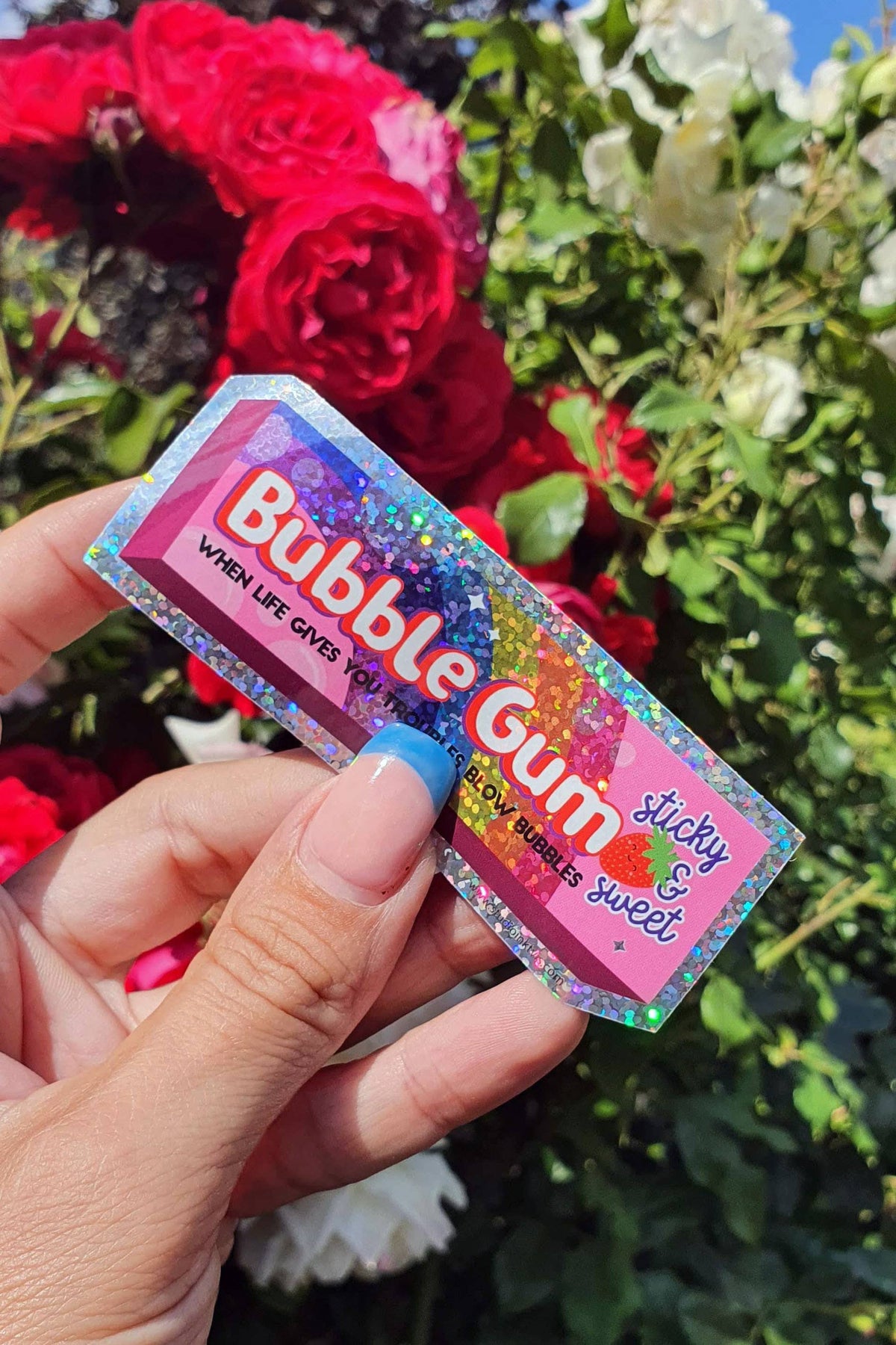 Glitter vinyl Bubble Gum sticker held in hand near flowers