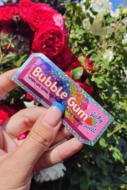 Glitter vinyl Bubble Gum sticker held in hand near flowers
