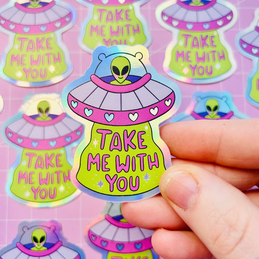 Holographic UFO sticker: lime alien in purple saucer with hearts, 'Take Me With You'.