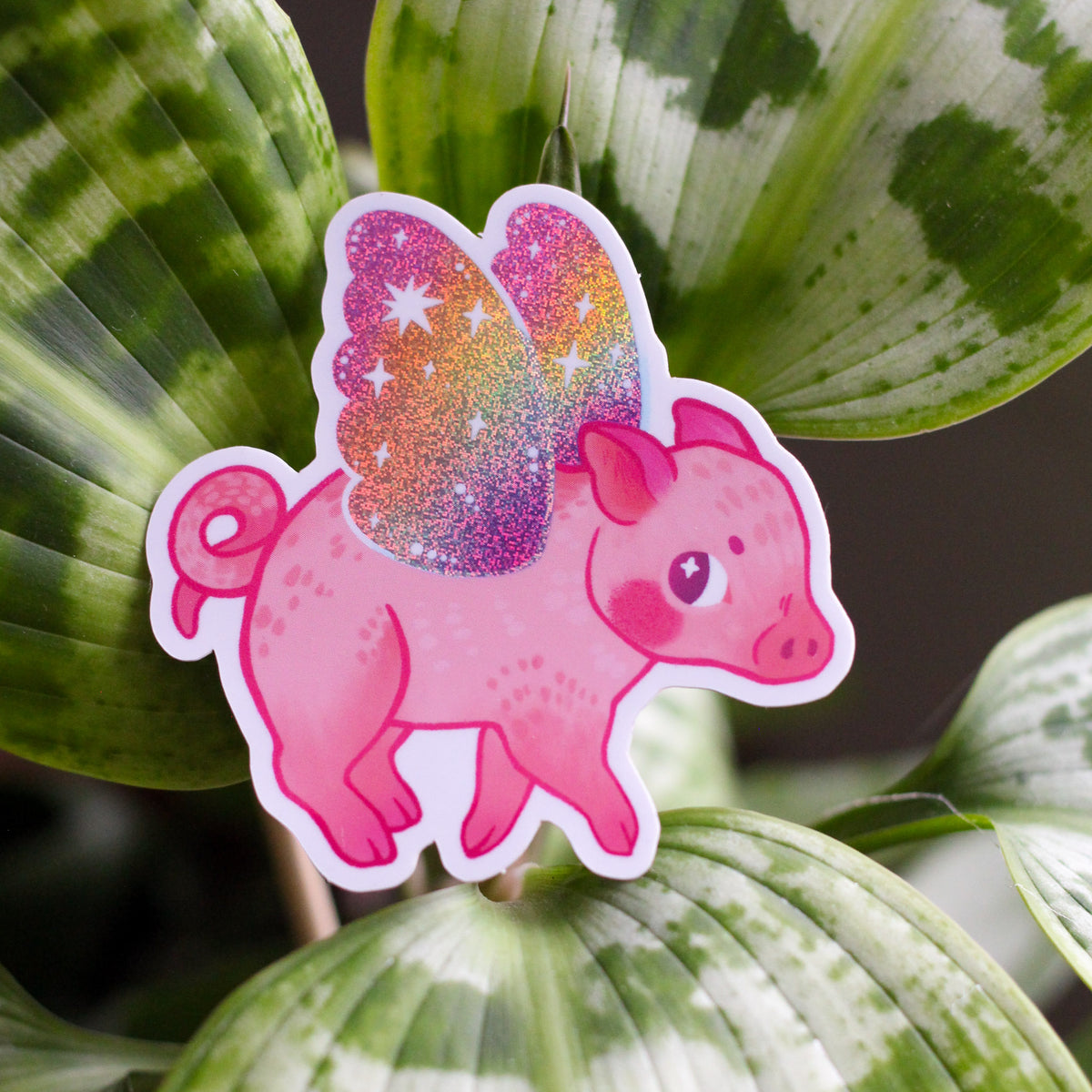 Pink flying pig vinyl sticker with glittery star pattern and white outline.