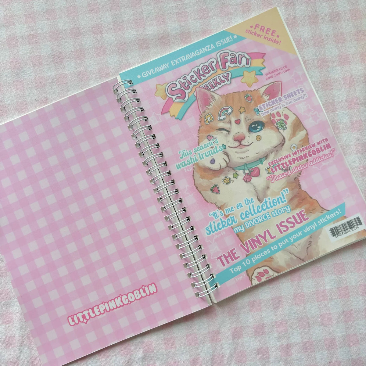 Pink spiral sticker book with illustrated cat face and sticker sheet