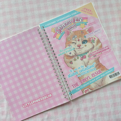 Pink spiral sticker book with illustrated cat face and sticker sheet