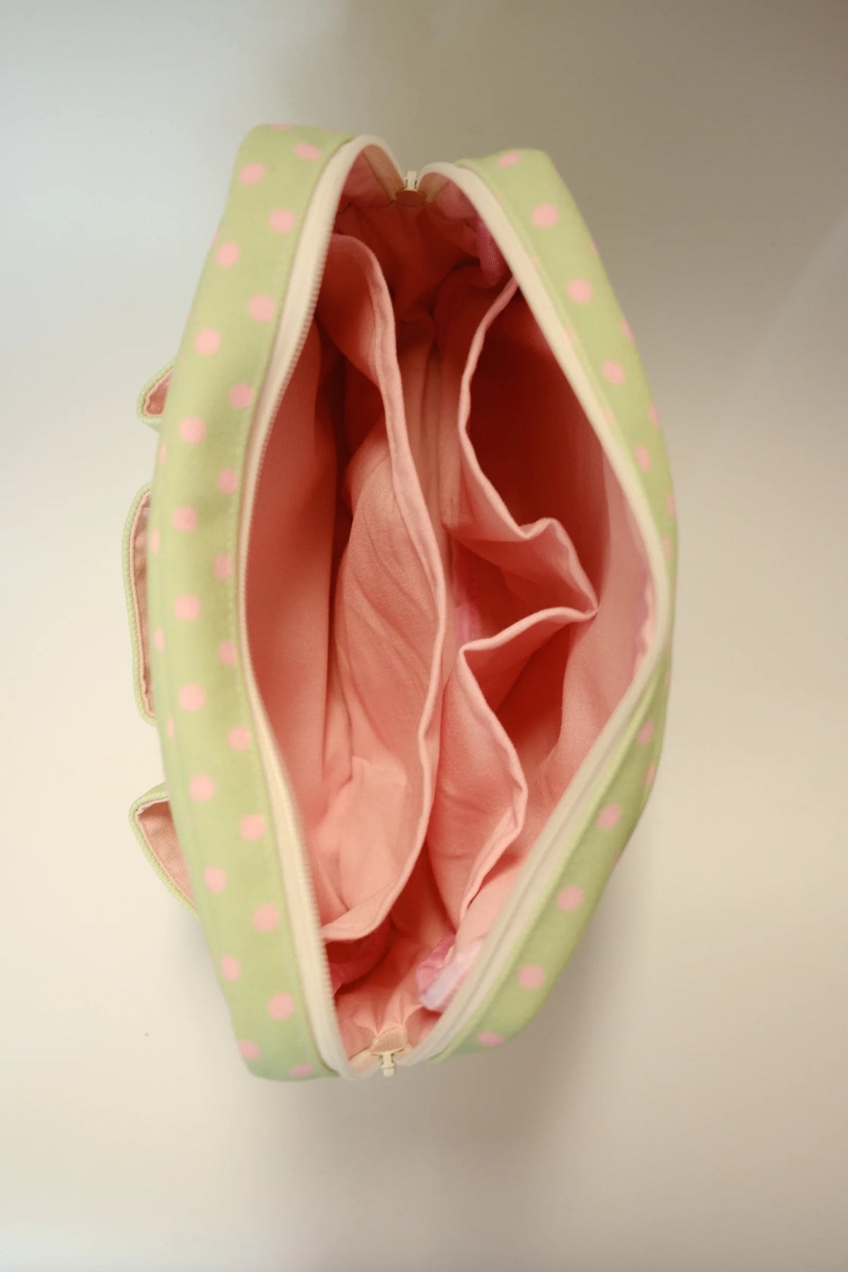 Green polka dot crafting pouch open to show pink-lined interior and side dividers