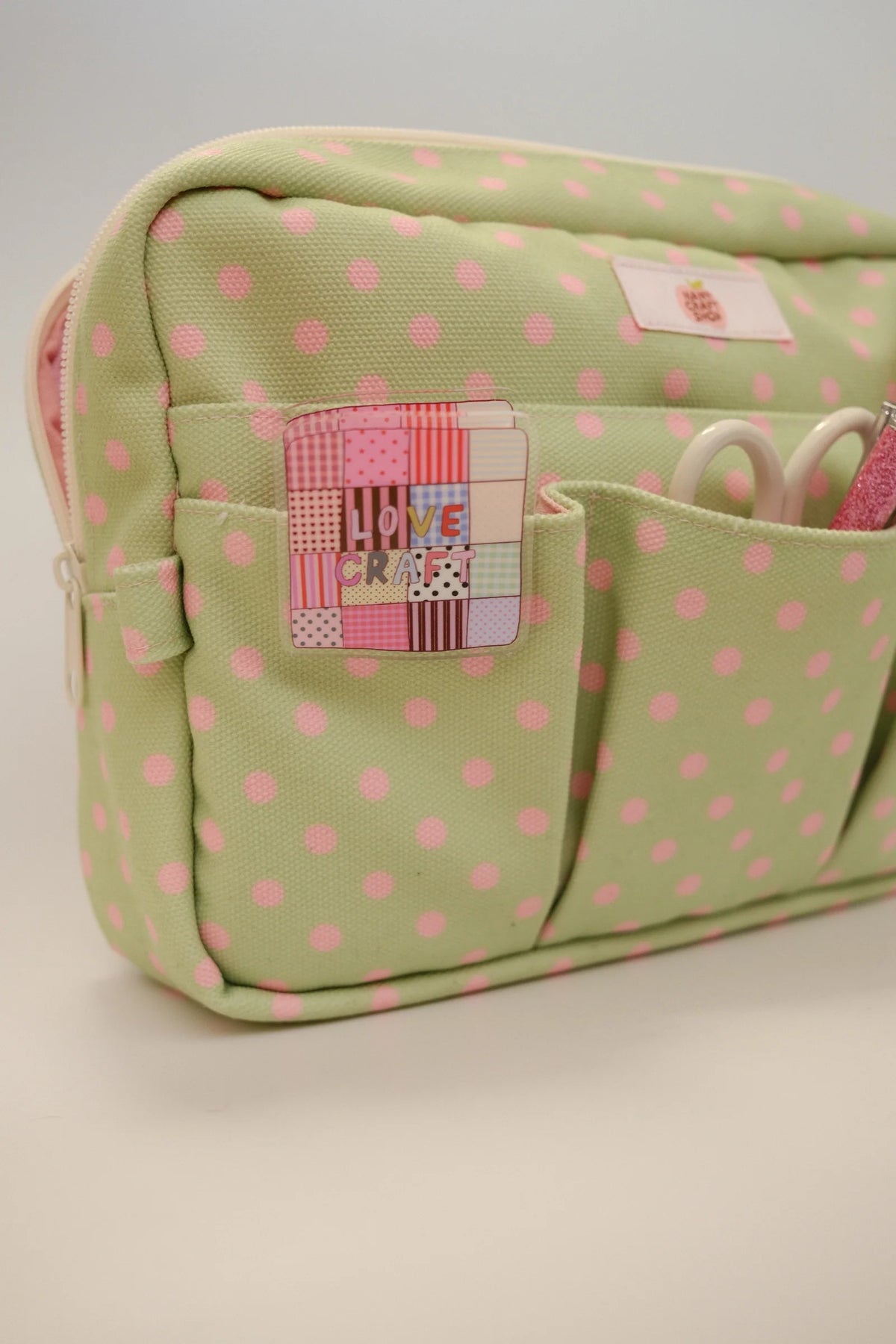 Green polka dot crafting pouch with front organizer pockets and logo patch